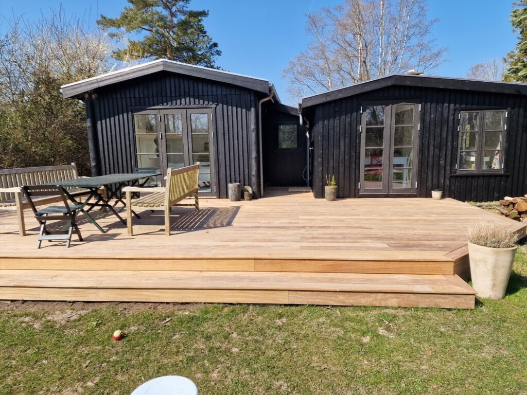 Sort træhus med stor terrasse og havemøbler
