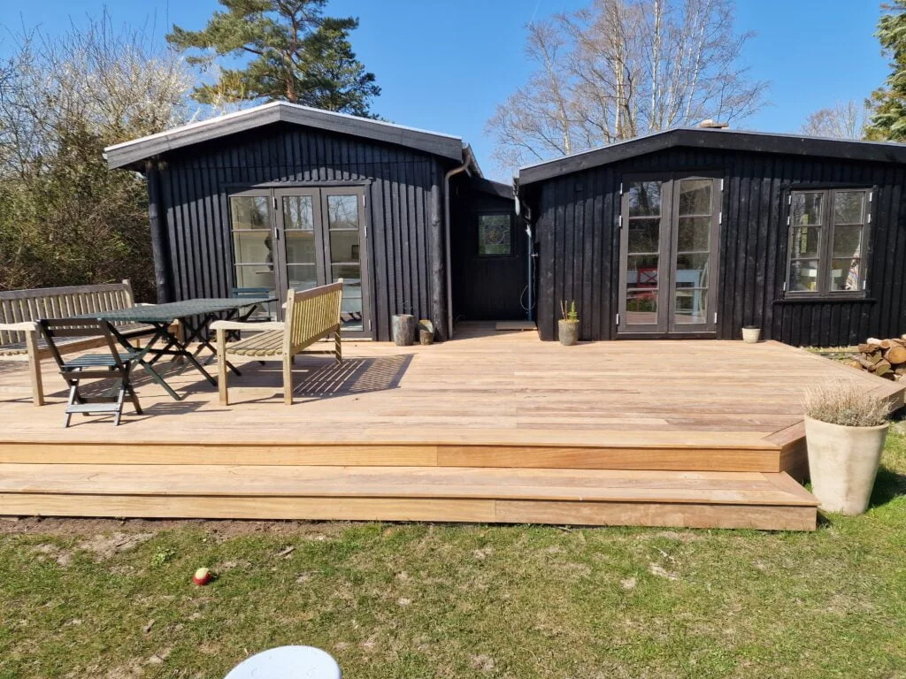 Sort træhus med stor terrasse og havemøbler