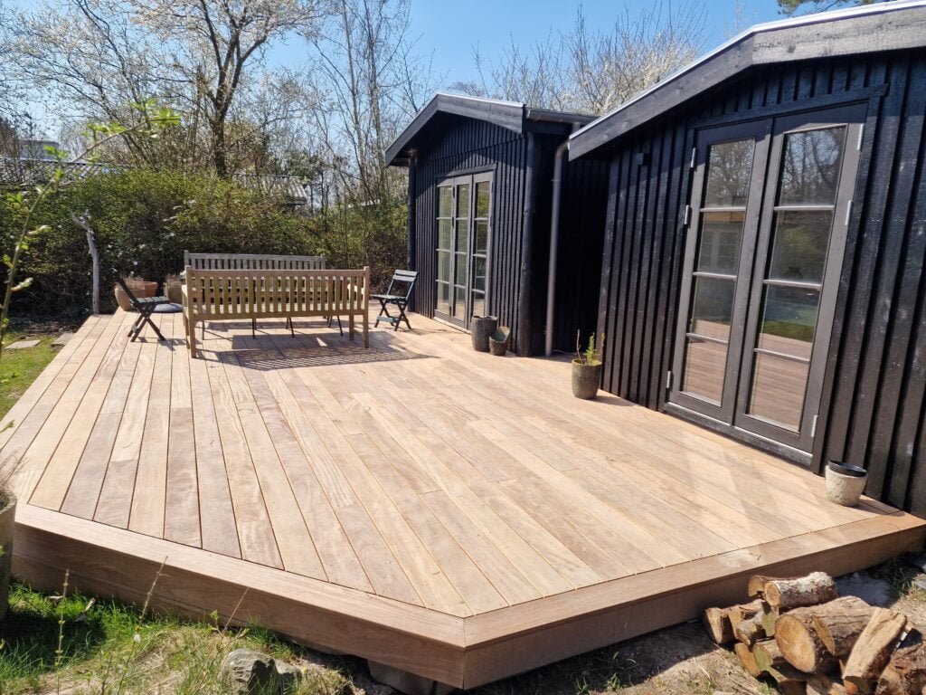 Træterrasse ved sort træhus med havemøbler