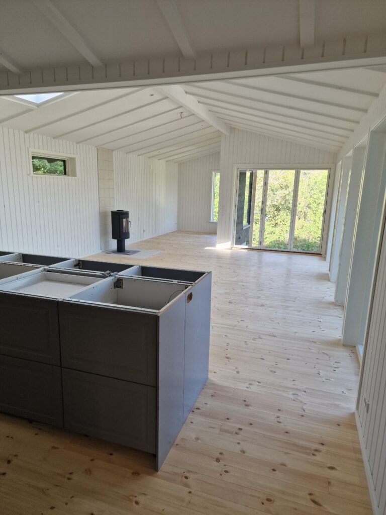 Lyst stue med trægulv og store vinduer